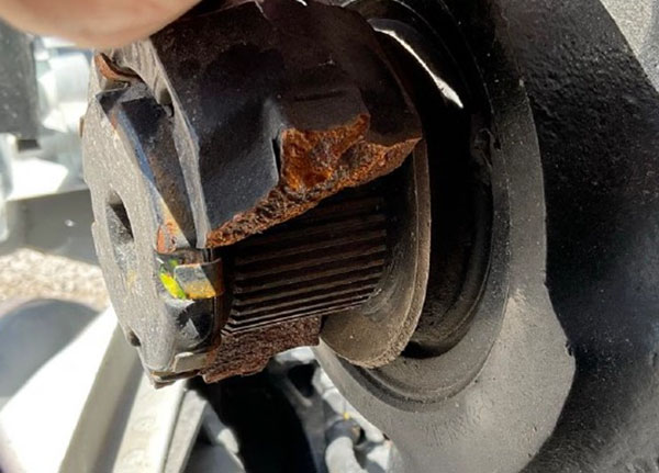 A close-up view of a metal mechanical component showing severe corrosion and signs of material fatigue, including surface pitting and a fractured edge, indicative of a metal failure analysis.