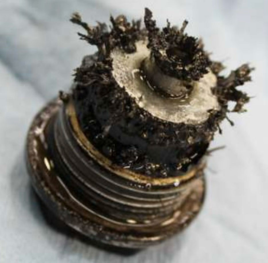 Close-up of a heavily damaged mechanical component showing significant material wear, used for forensic analysis of a claimed equipment malfunction.