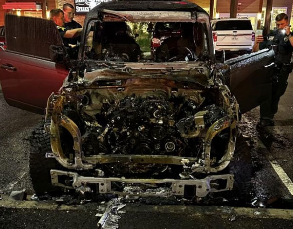 Front view of a fire-damaged vehicle showing significant burn patterns and thermal damage, used for origin and cause investigation.